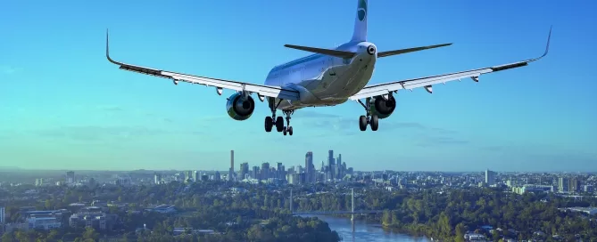 An airplane fitted with advanced Softinway turbomachinery approaches for landing over a cityscape, gliding gracefully above a river with the skyline in the background.