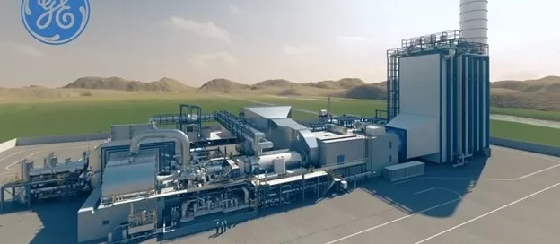 Industrial facility with interconnected turbomachinery and a tall cylindrical structure, set against a landscape of hills and open skies. Softinway logo in the top left corner.