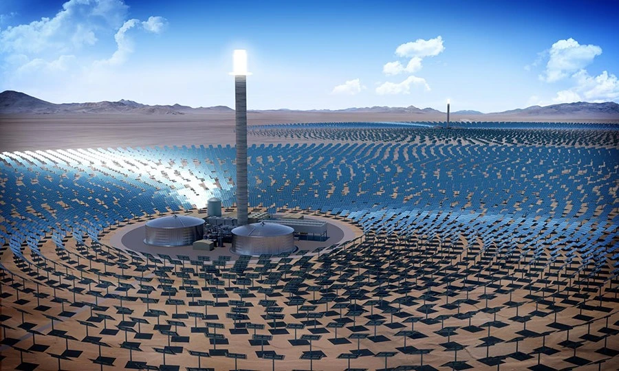 Aerial view of a solar power plant with numerous solar panels surrounding a central tower in a desert landscape under a blue sky.