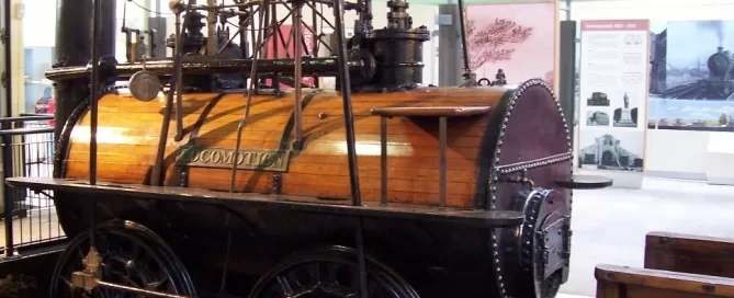 A vintage steam locomotive displayed indoors with wooden and metal components, showcasing historical engineering design.