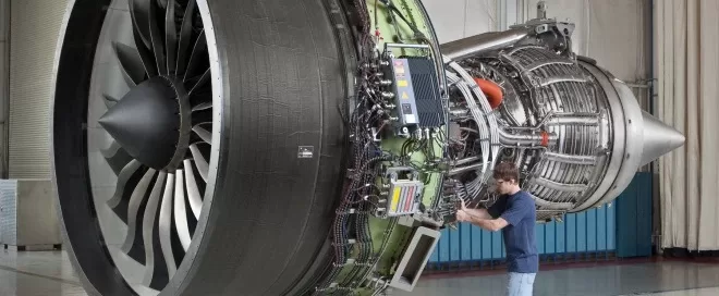 Technician working on a large jet engine in a hangar.