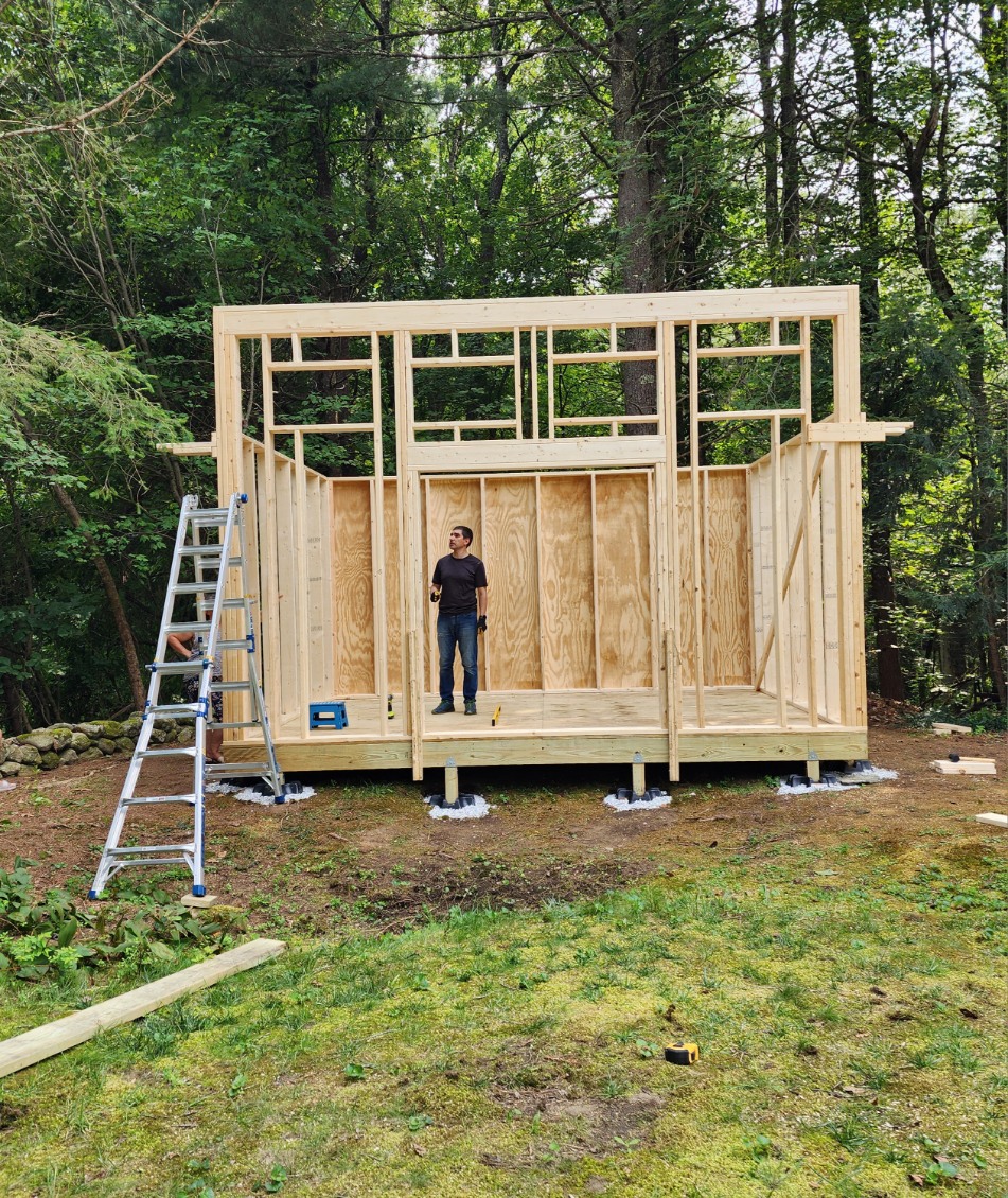 Image of Maksym in his backyard building a shed for his family