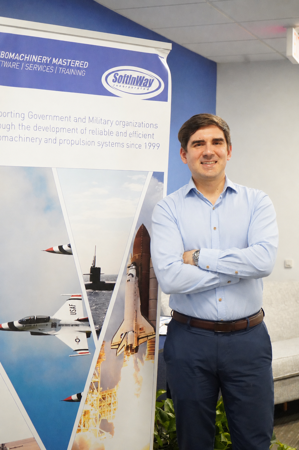 Image of Maksym Burlaka in SoftInWay Headquarters smiling next to SoftInWay sign during his career at SoftInWay