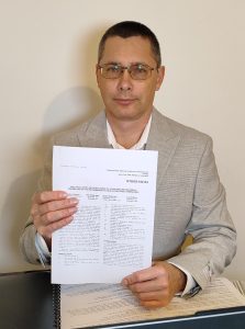 Image of Ievgen Rublevskyi’s holding his co-authored ASME published paper with working at SoftInWay